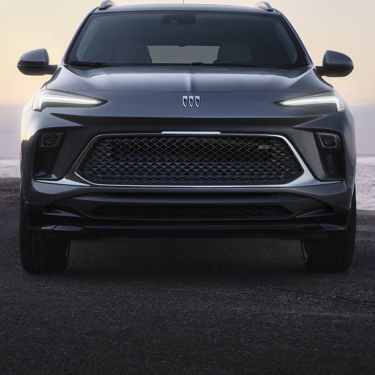 Close-up of the Front View of the Buick 2026 Encore GX ST Sporty SUV Parked on the Beach at Sunset