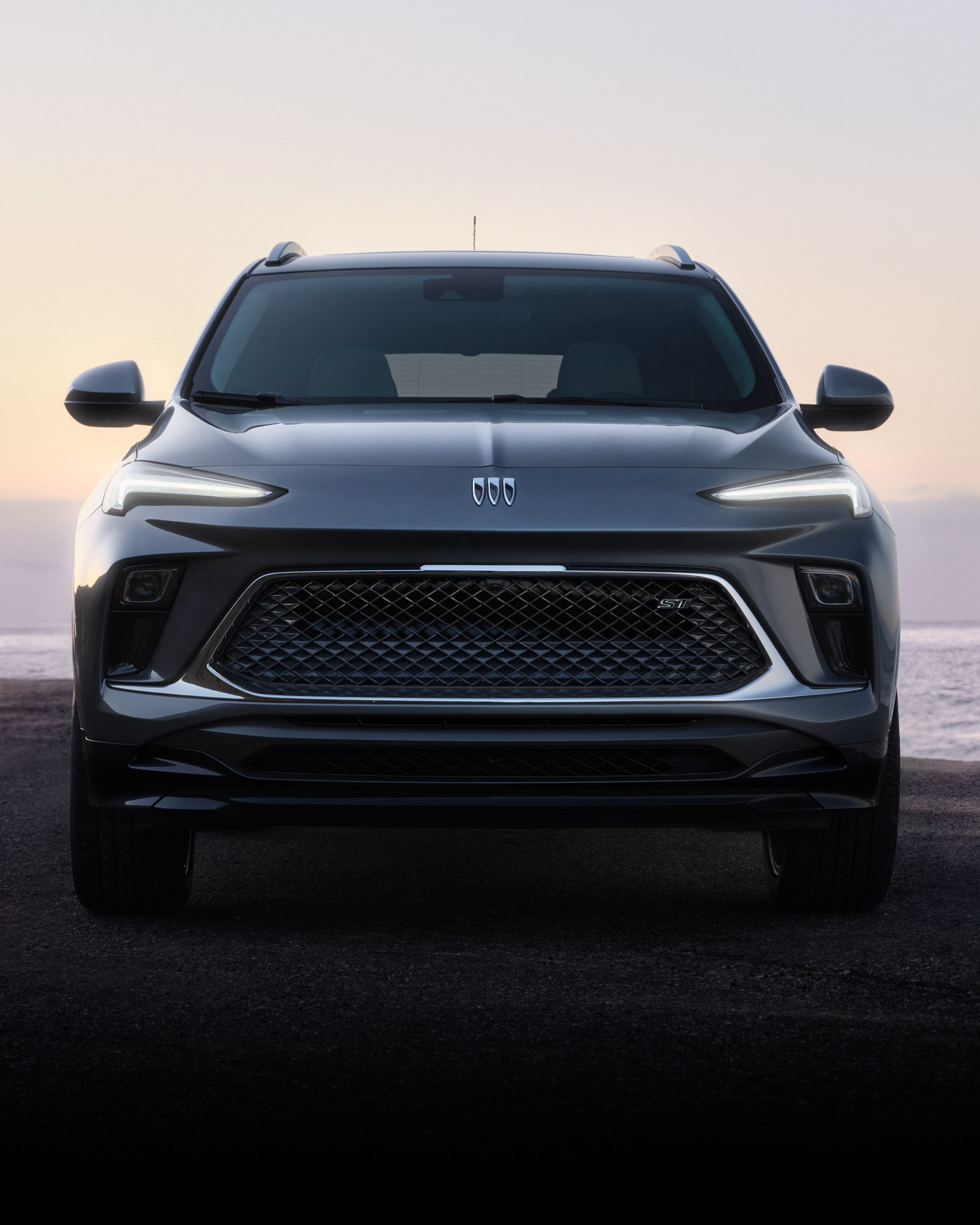 Close-up of the Front View of the Buick 2026 Encore GX ST Sporty SUV Parked on the Beach at Sunset