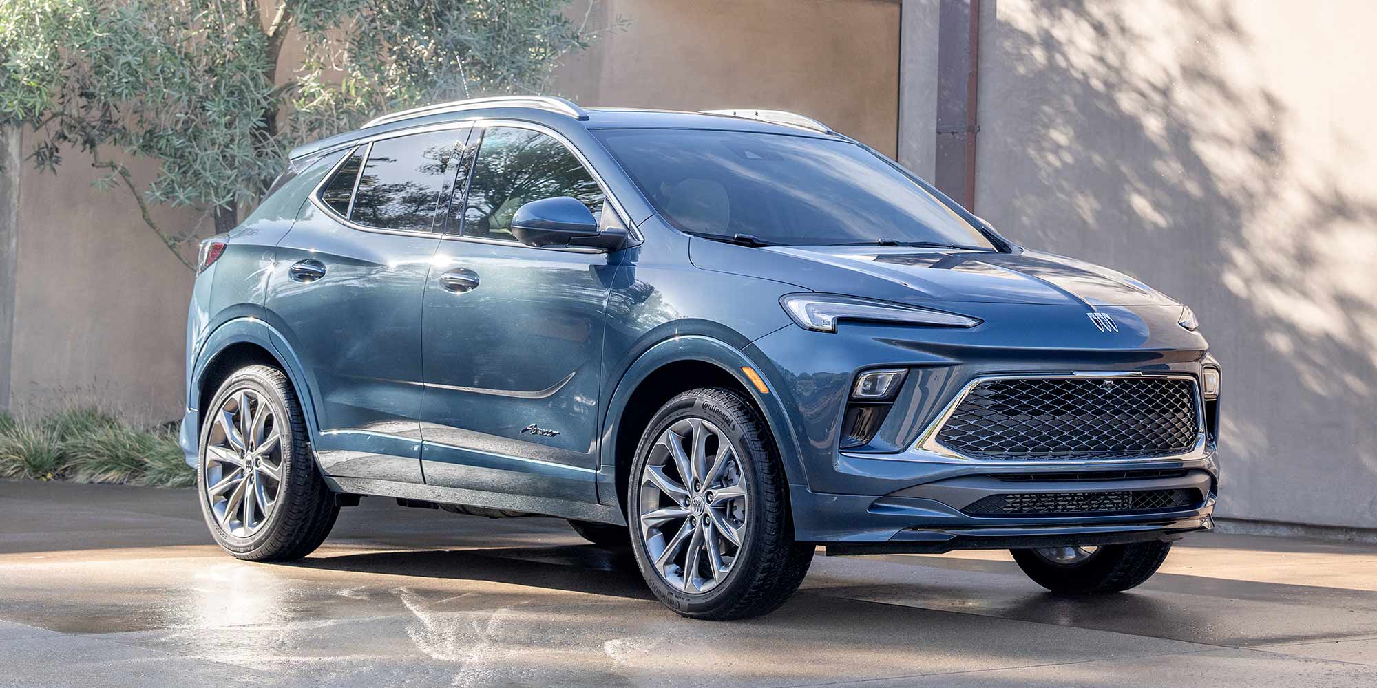 Front Three-Quarters View of the 2026 Buick Encore GX Small SUV Parked in a Driveway While the Sun Shines