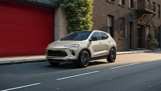 The 2026 Buick Encore GX Sports Touring SUV in the Color Ceramic Driving Down a City Street