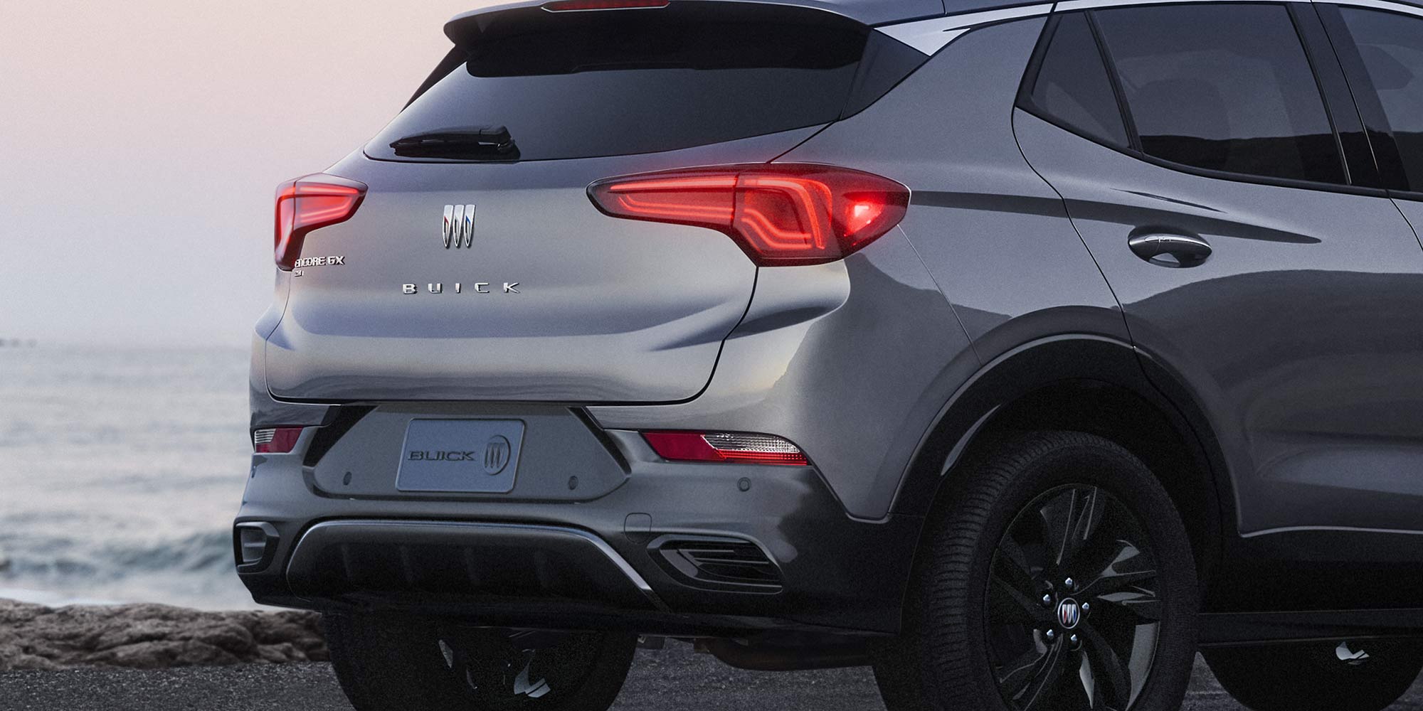 Rear Three-Quarters View of the 2026 Buick Encore GX Avenir Luxury SUV Parked on the Beach at Sunset