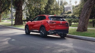 Rear Three-Quarters View of the 2026 Buick Envision Compact SUV Driving Through a Neighborhood