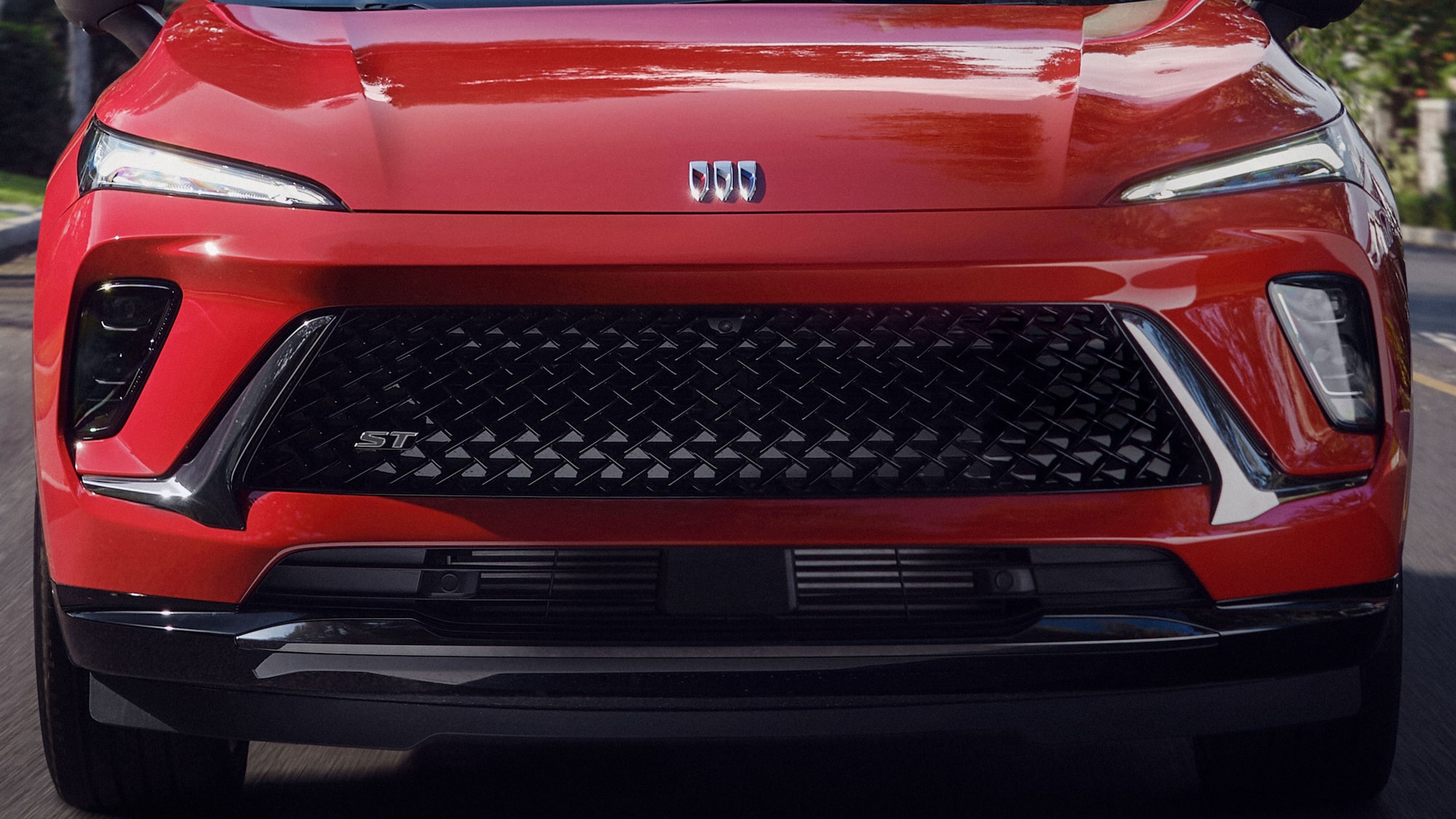 Front View of the 2026 Buick Envision ST Sporty Compact SUV Driving Down a Black Top Road