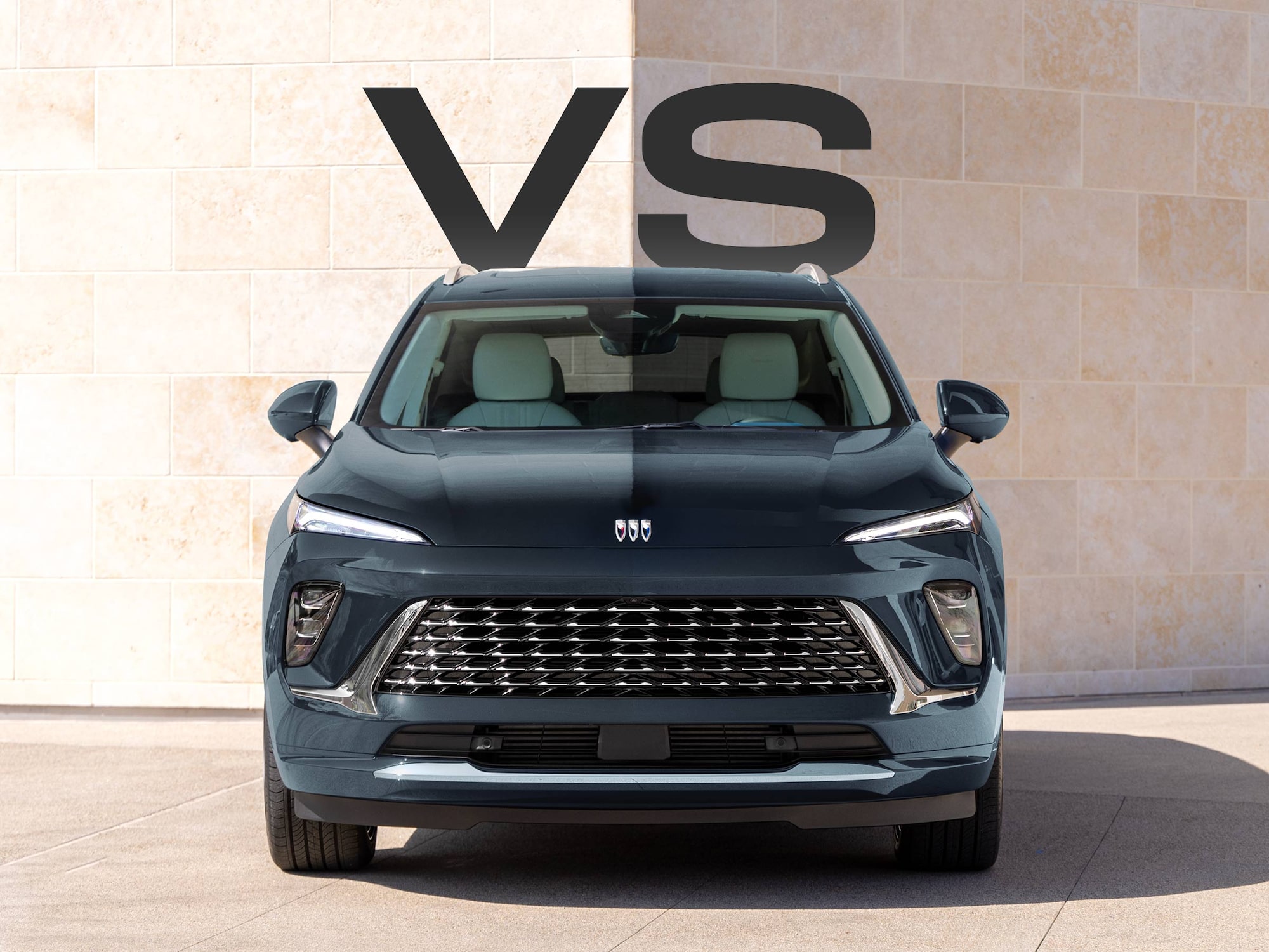 A Front View of the Dark Blue 2025 Buick Envision SUV Parked Against a Modern Stone Wall