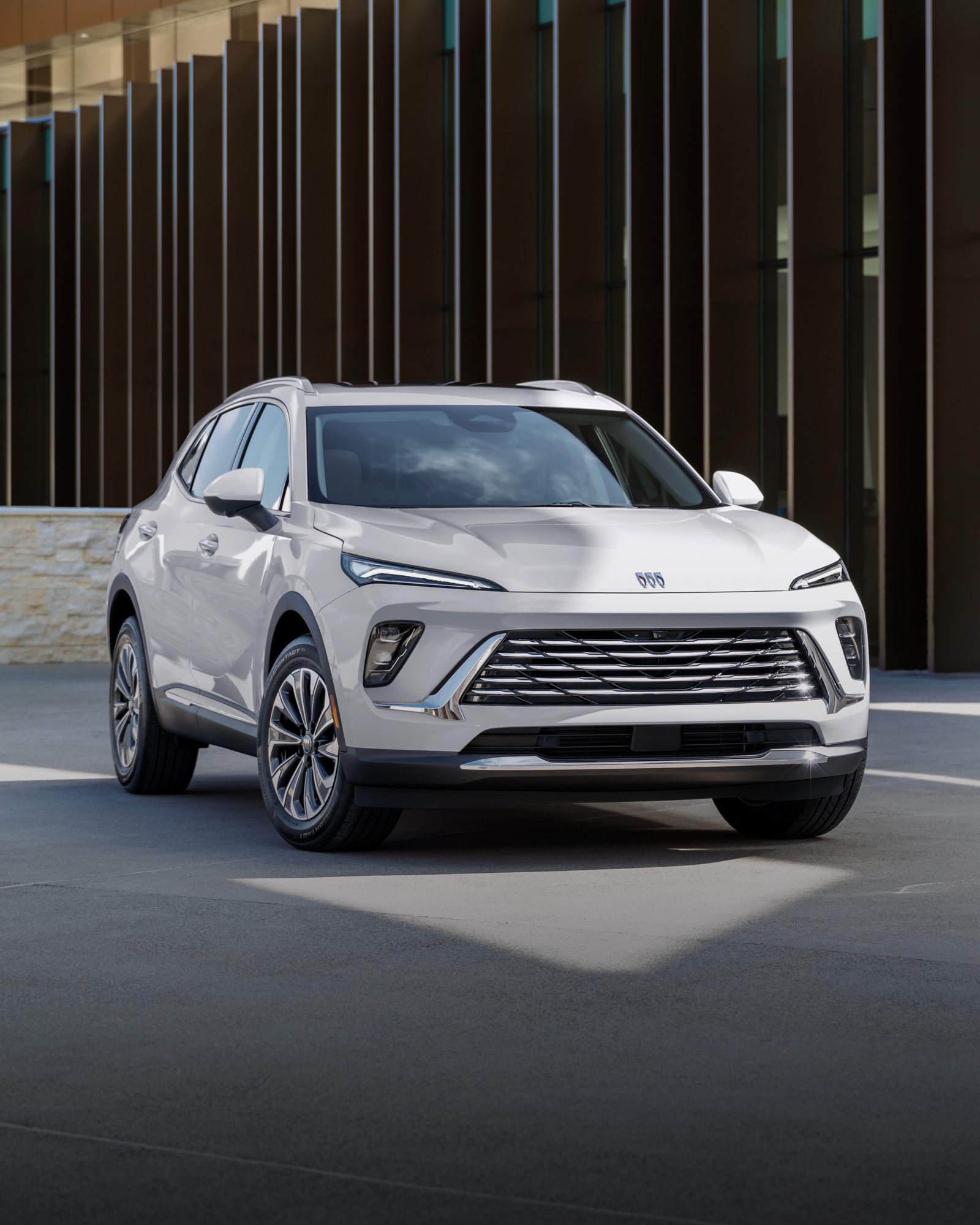 Front Three-Quarters View of the 2026 Buick Envision Preferred 5 Passenger SUV Driving Down a Tree Lined Road