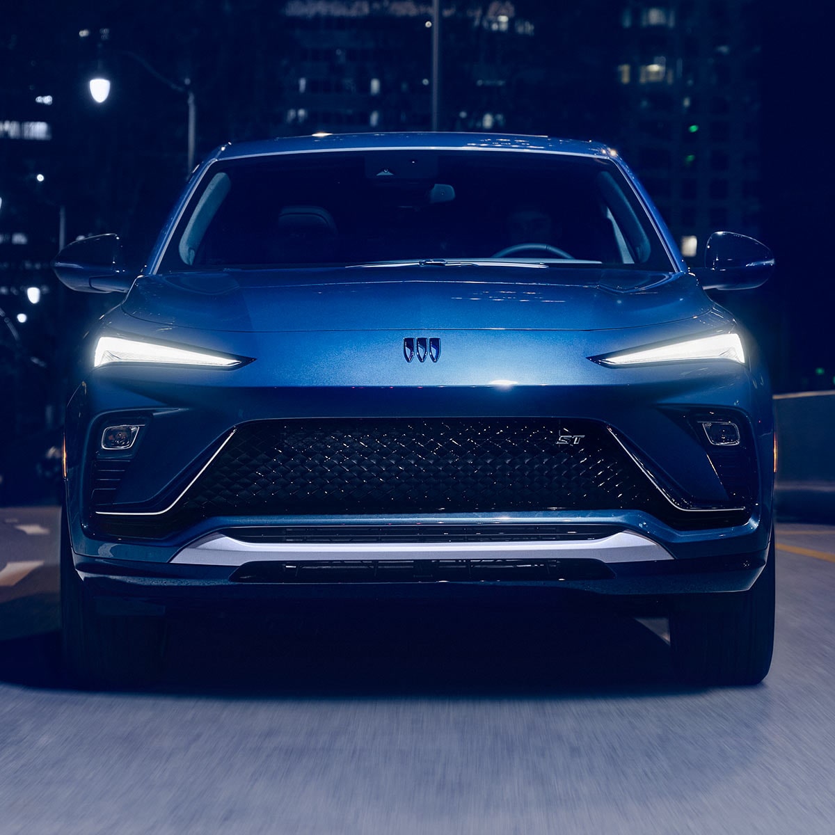 The 2026 Buick Envista Sport Touring Driving Out of the City Under a Street Light