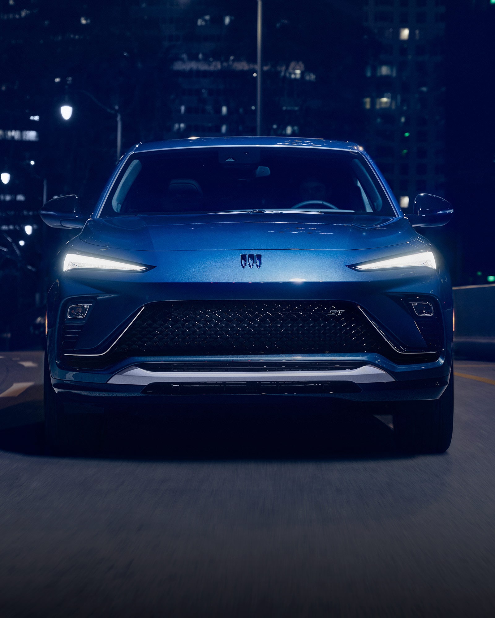 The 2026 Buick Envista Sport Touring Driving Out of the City Under a Street Light
