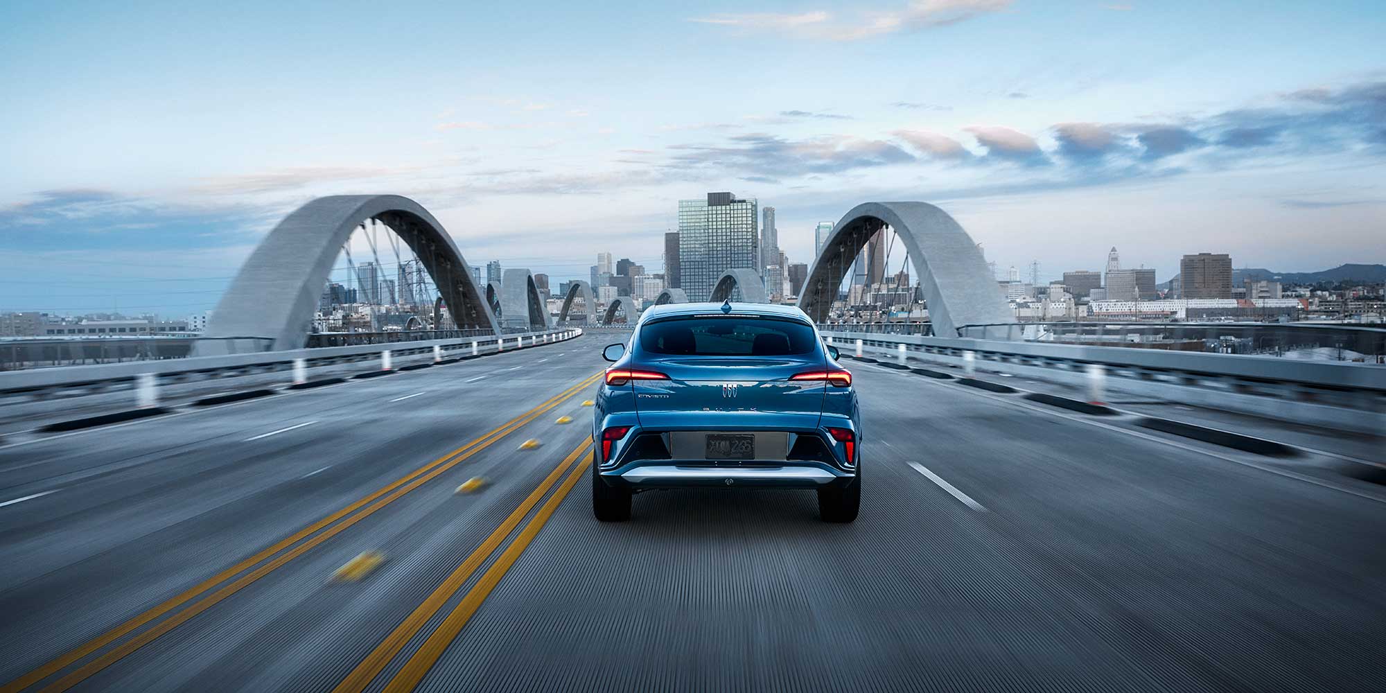Rear View of a 2026 Buick Envista Driving Down a Bridge on the Way to the City