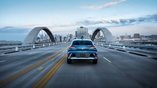 Rear View of a 2026 Buick Envista Driving Down a Bridge on the Way to the City