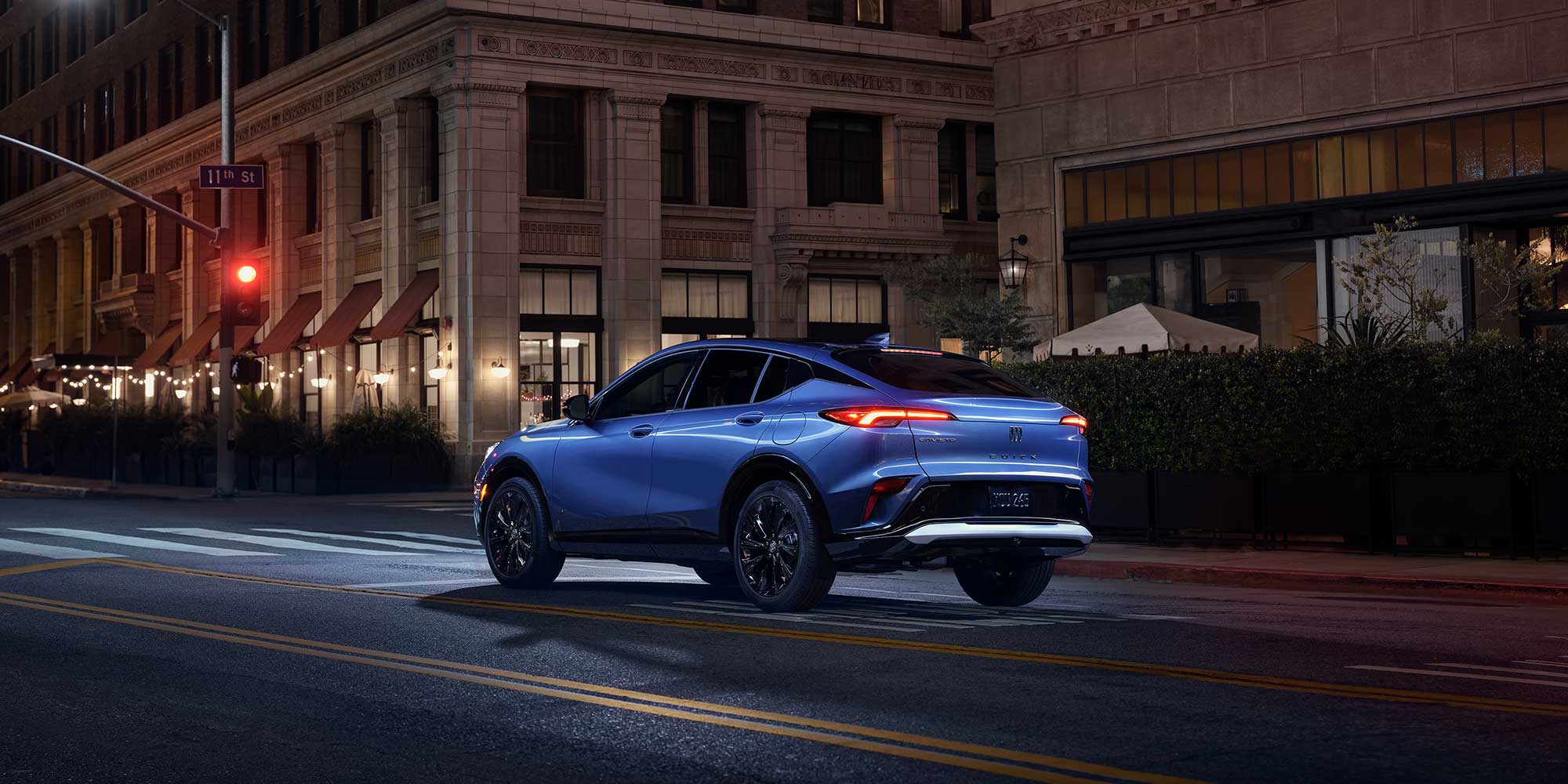 Three-quarters Rear View of the 2026 Buick Envista Driving Down Through the City at Night