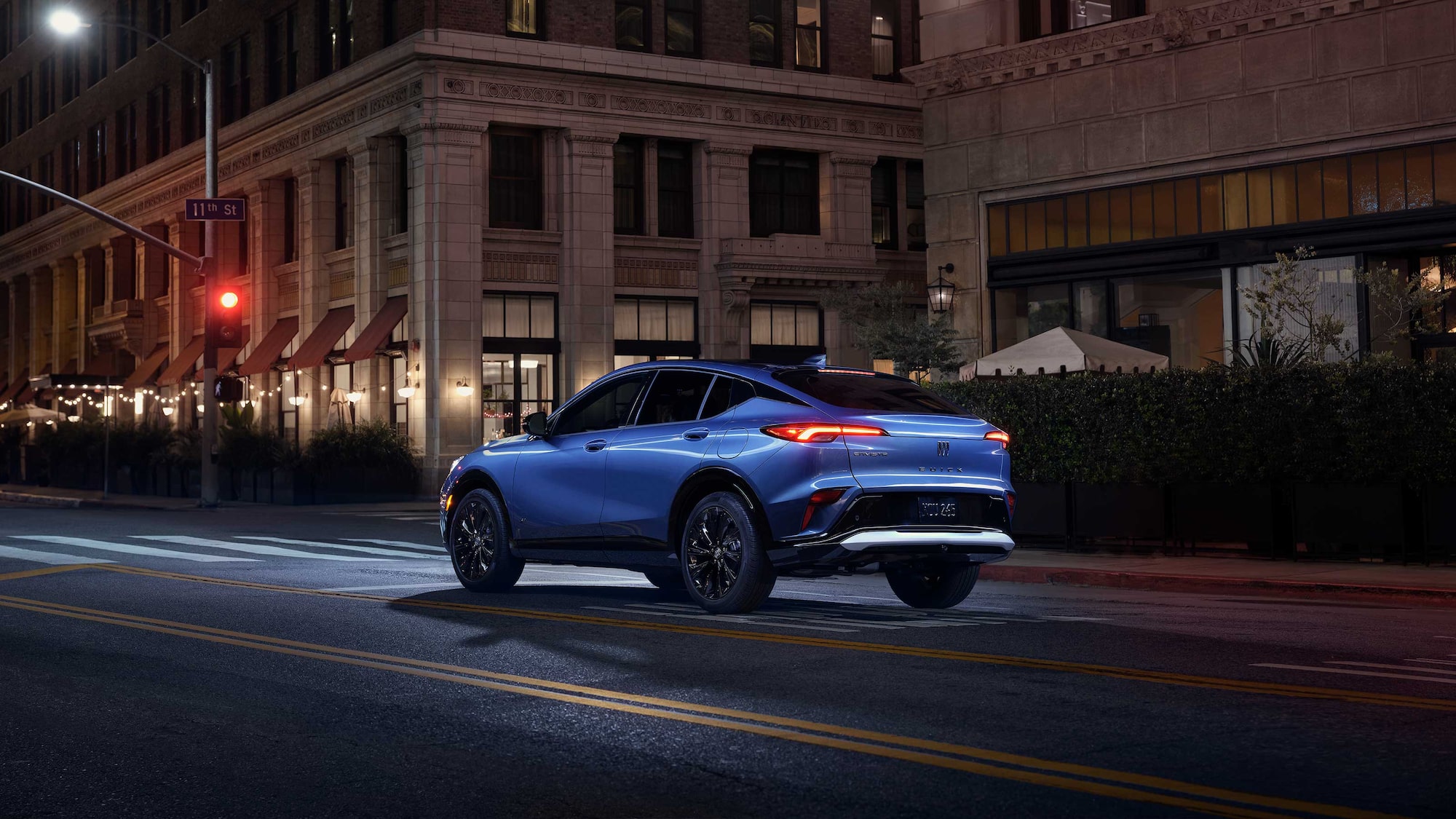 Three-quarters Rear View of the 2026 Buick Envista Driving Down Through the City at Night