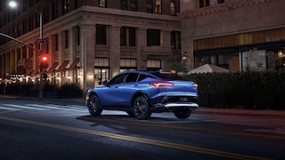 Three-quarters Rear View of the 2026 Buick Envista Driving Down Through the City at Night