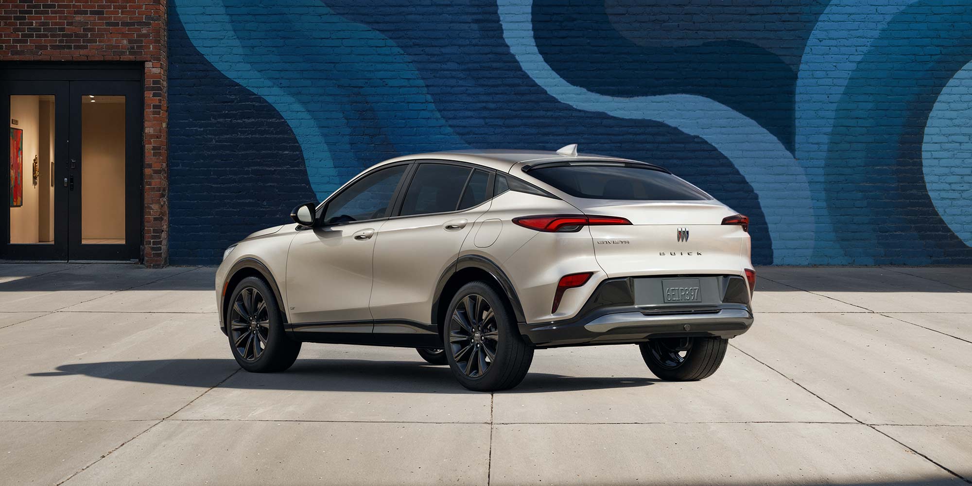 Rear View of the 2026 Buick Envista ST SUV with the Studio Series Package Parked Next to a City Building Covered with a Colorful Abstract Mural