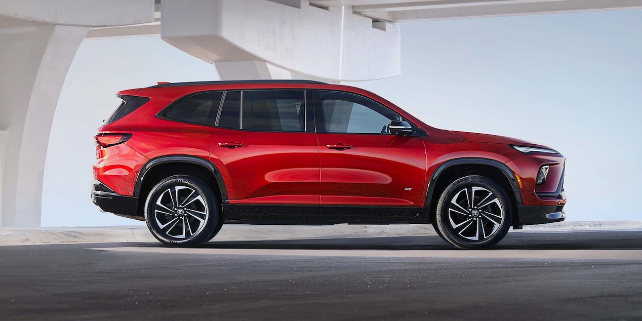 A Red Buick Enclave SUV Parked in Profile under a Modern Architectural Archway