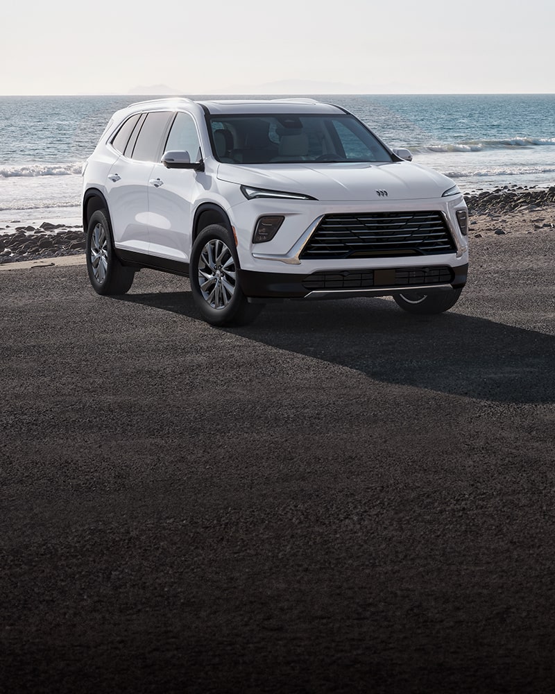A White Buick Enclave SUV Parked on a Beach Road with the Ocean in the Background