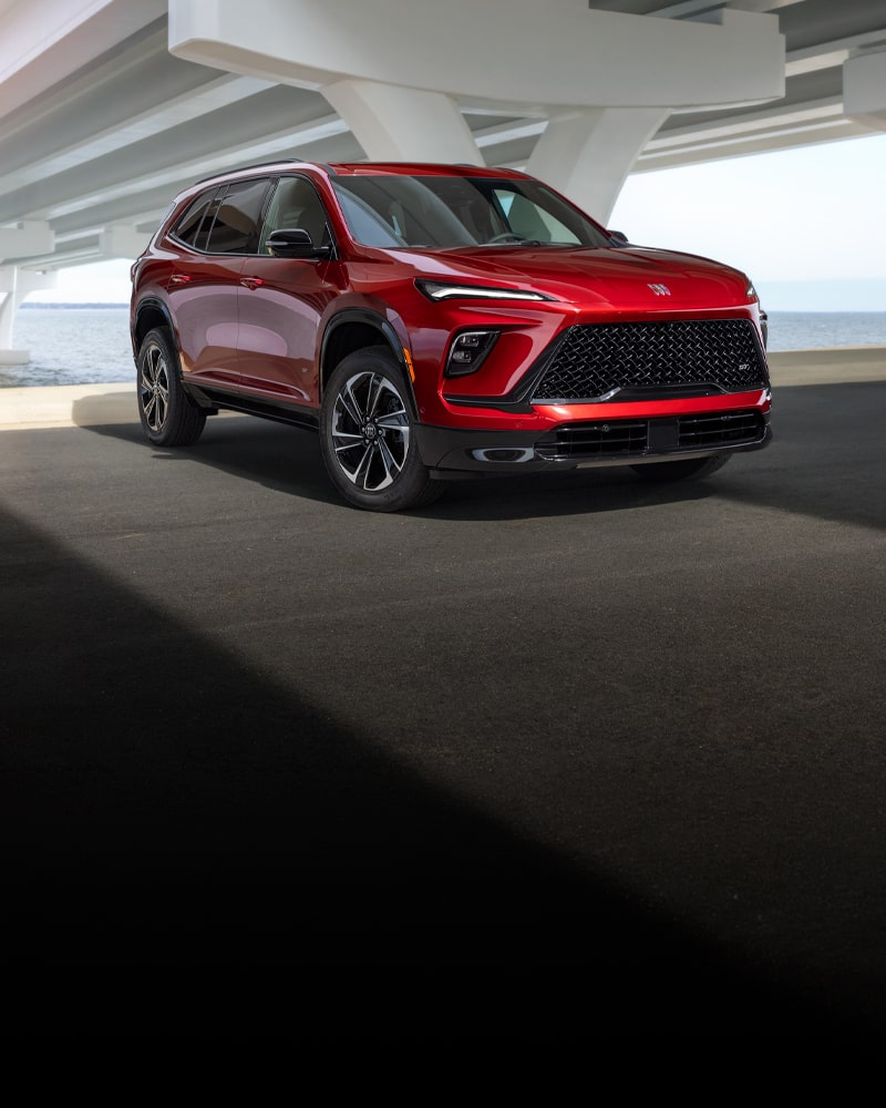 A Red Buick Enclave SUV Parked Under an Overpass Next to the Water