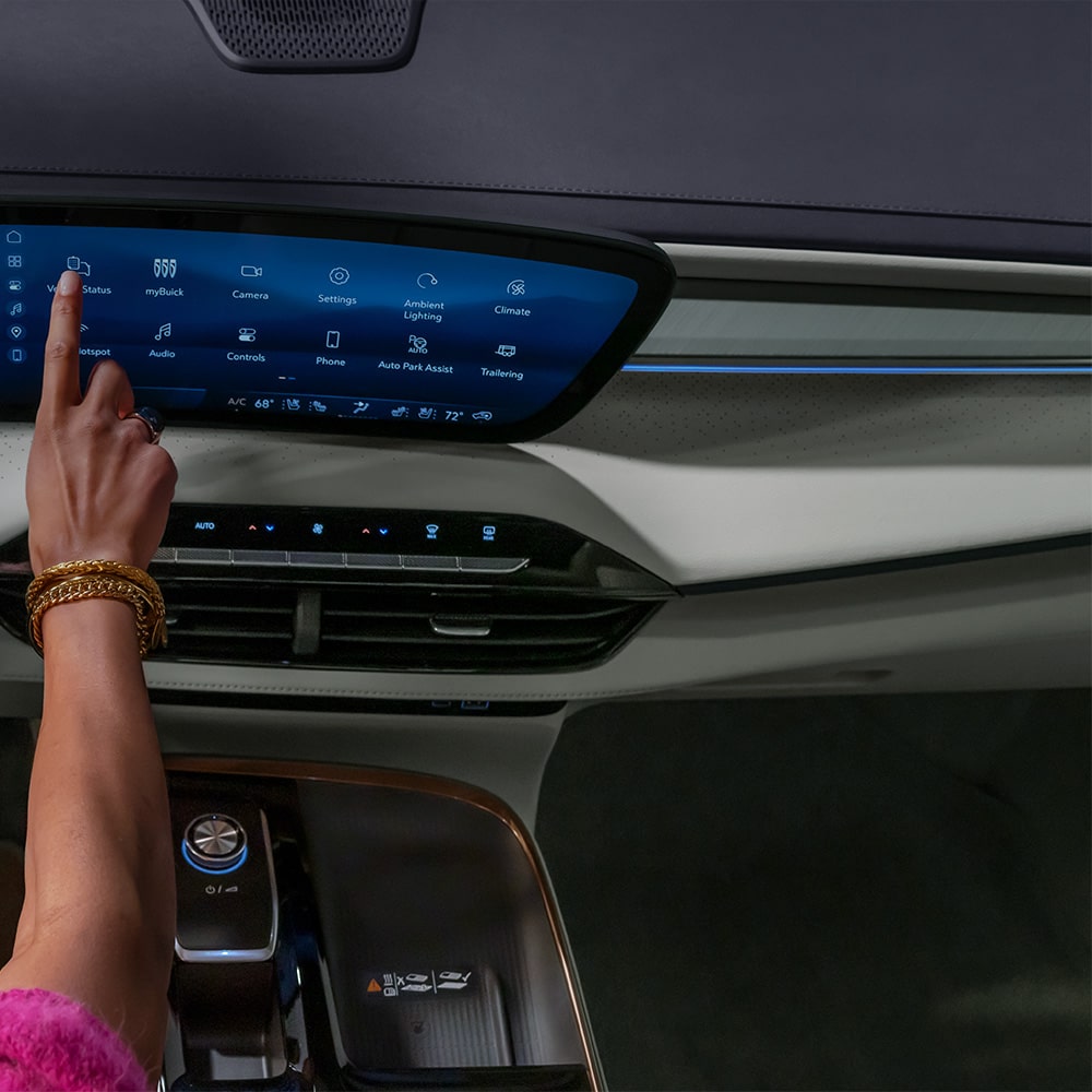 A Driver's Hand Interacts with the Expansive Curved Digital Display in a Modern Buick Interior, Featuring the Buick Logo on the Steering Wheel