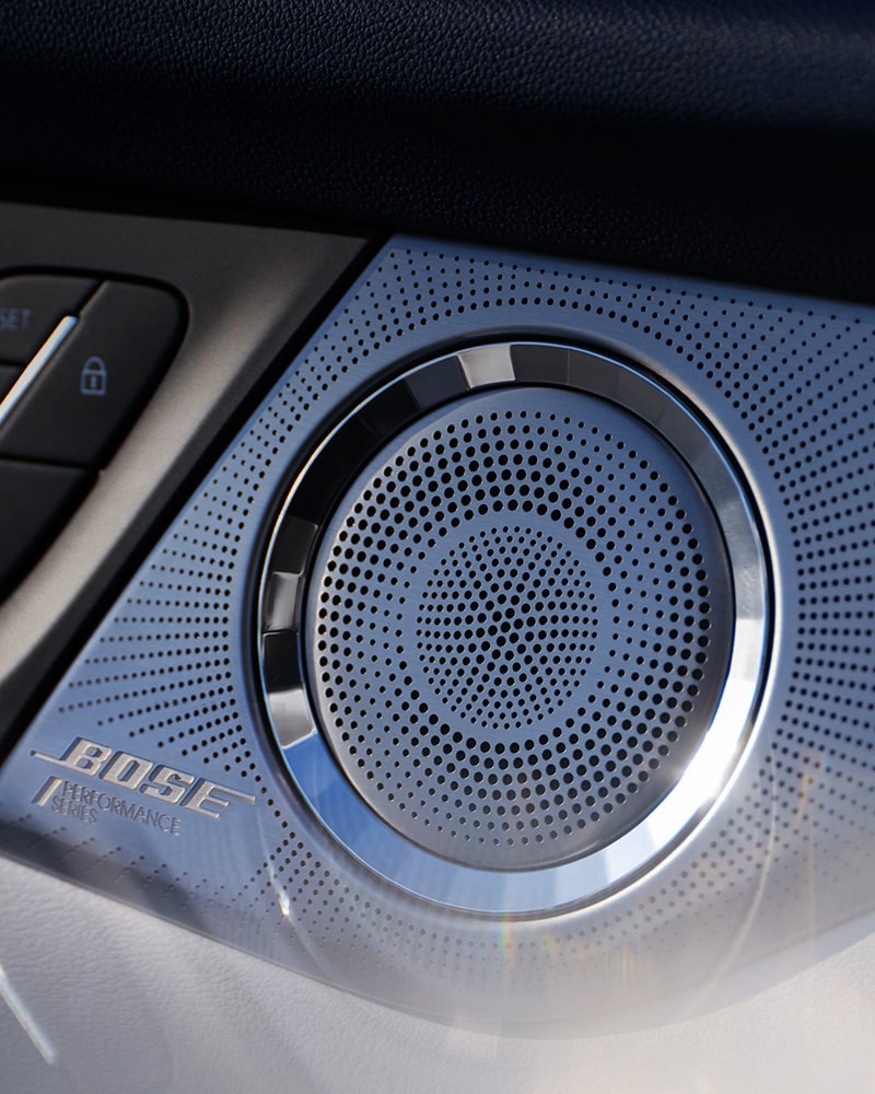 A Close-up of a Car Speaker Grille with a Silver BOSE Logo