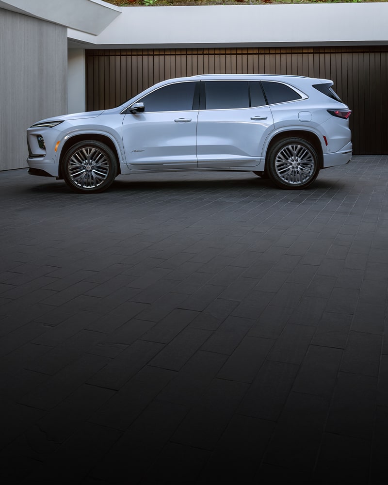A White Buick Enclave SUV Parked Next to a Modern Building with Dark Garage Doors
