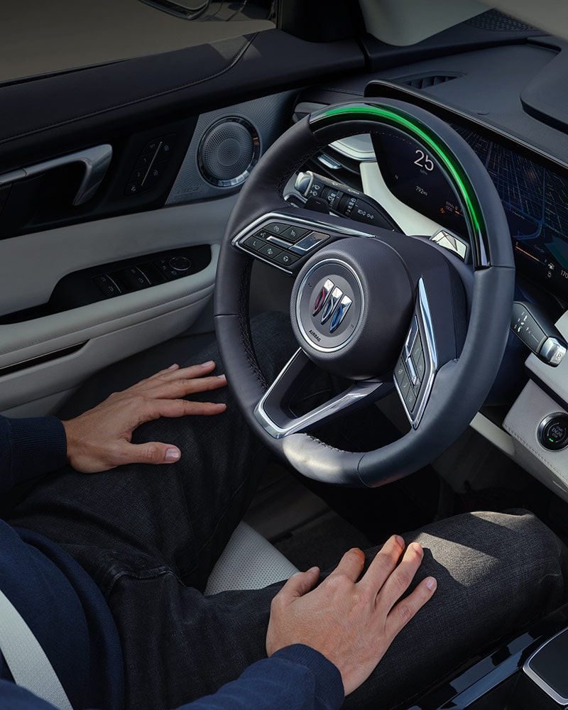 A Driver's Hand Resting on their Lap with a View of the Buick Steering Wheel and Car Door Panel
