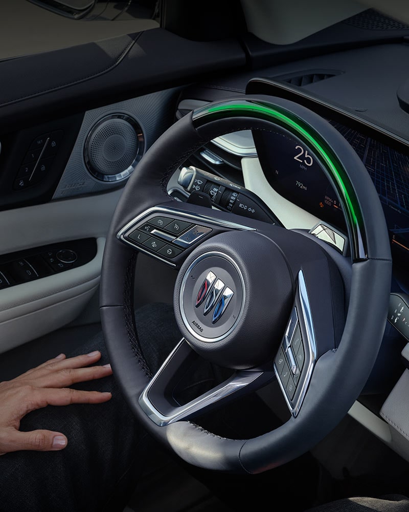 A Driver's Hand Resting on their Lap with a View of the Buick Steering Wheel and Car Door Panel