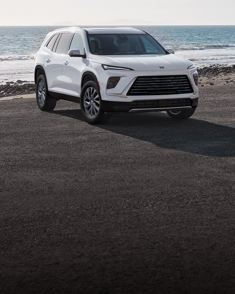 A White Buick Enclave SUV Parked on a Beach Road with the Ocean in the Background