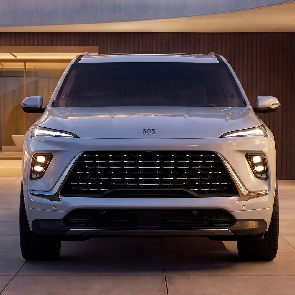 The Front View of a White Buick Enclave Avenir SUV Parked in Front of a Modern Building