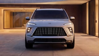 The Front View of a White Buick Enclave Avenir SUV Parked in Front of a Modern Building