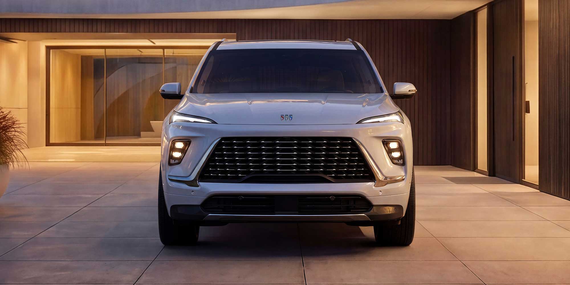 The Front View of a White Buick Enclave Avenir SUV Parked in Front of a Modern Building