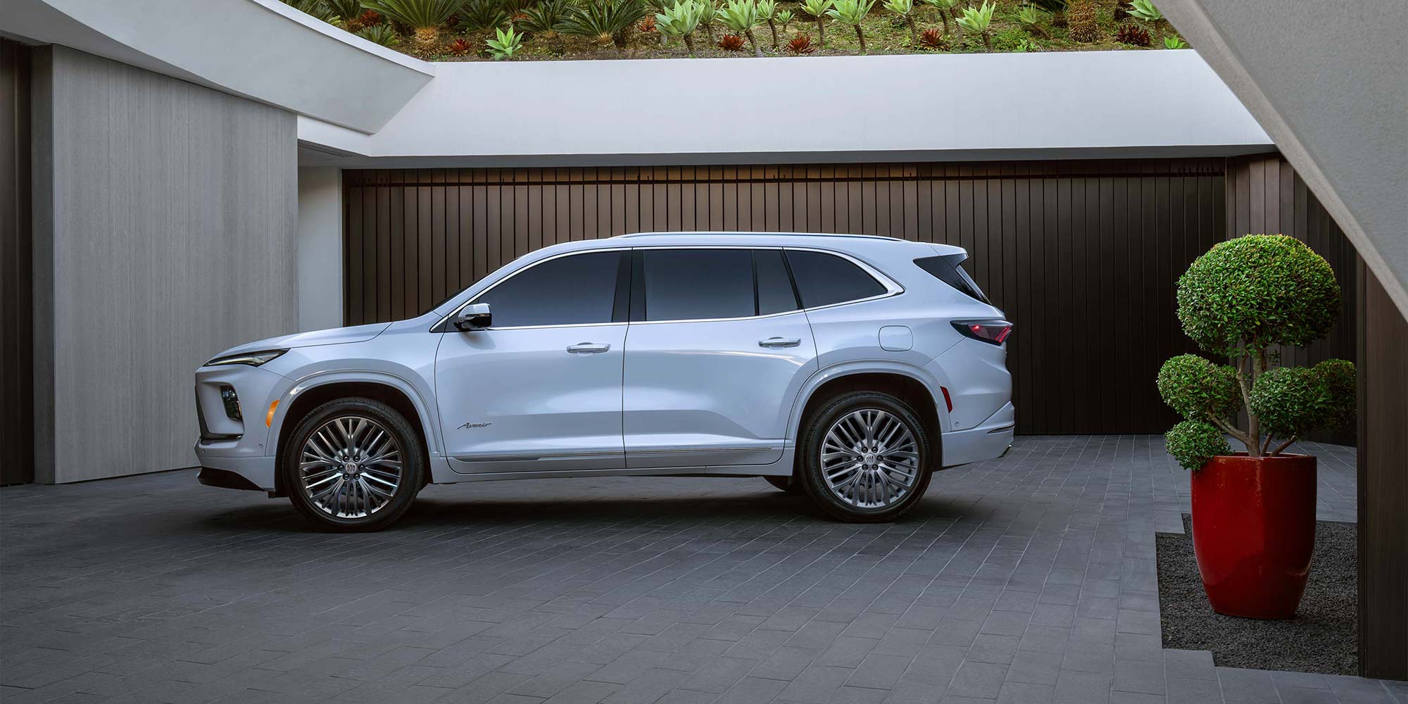A White Buick Enclave SUV Parked Next to a Modern Building with Dark Garage Doors