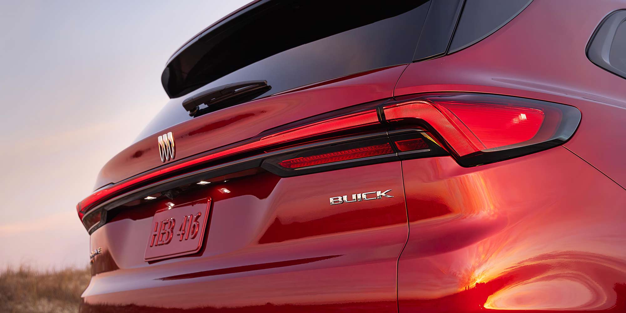 The Rear View of a Red Buick Enclave SUV with a Buick Logo and License Plate Displayed
