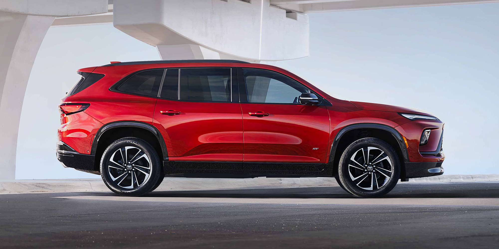 A Red Buick Enclave SUV Parked in Profile under a Modern Architectural Archway