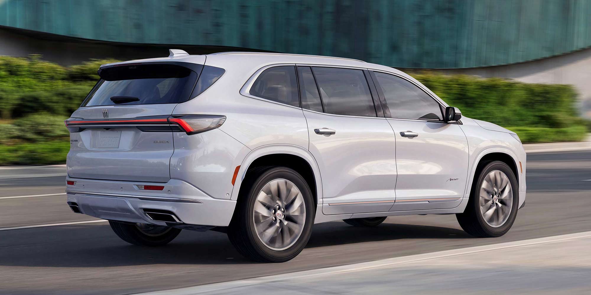 The Rear Angle of a White Buick Enclave Avenir SUV Driving on a Road