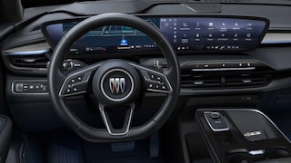 The Modern Interior Dashboard of a Buick Vehicle with a Wide Curved Digital Display and the Buick Logo on the Steering Wheel