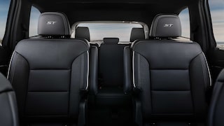 An Interior View of a Car's Second-Row Seating with Two Dark Gray Captain's Chairs and 'ST' Embroidery