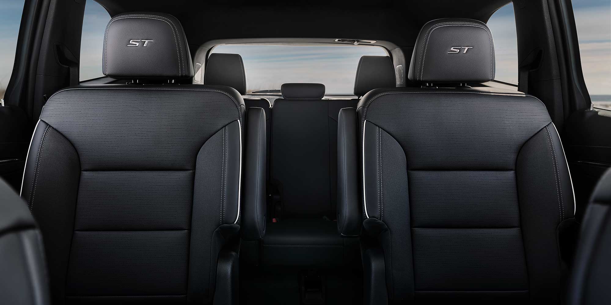 An Interior View of a Car's Second-Row Seating with Two Dark Gray Captain's Chairs and 'ST' Embroidery