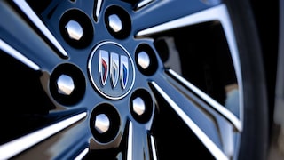 A Close-up View of a Glossy Black Car Wheel with Silver Spokes and the Buick Logo in the Center