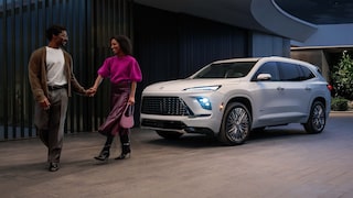 A Couple Holding Hands and Walking Away From a White Buick Enclave SUV Parked Outside