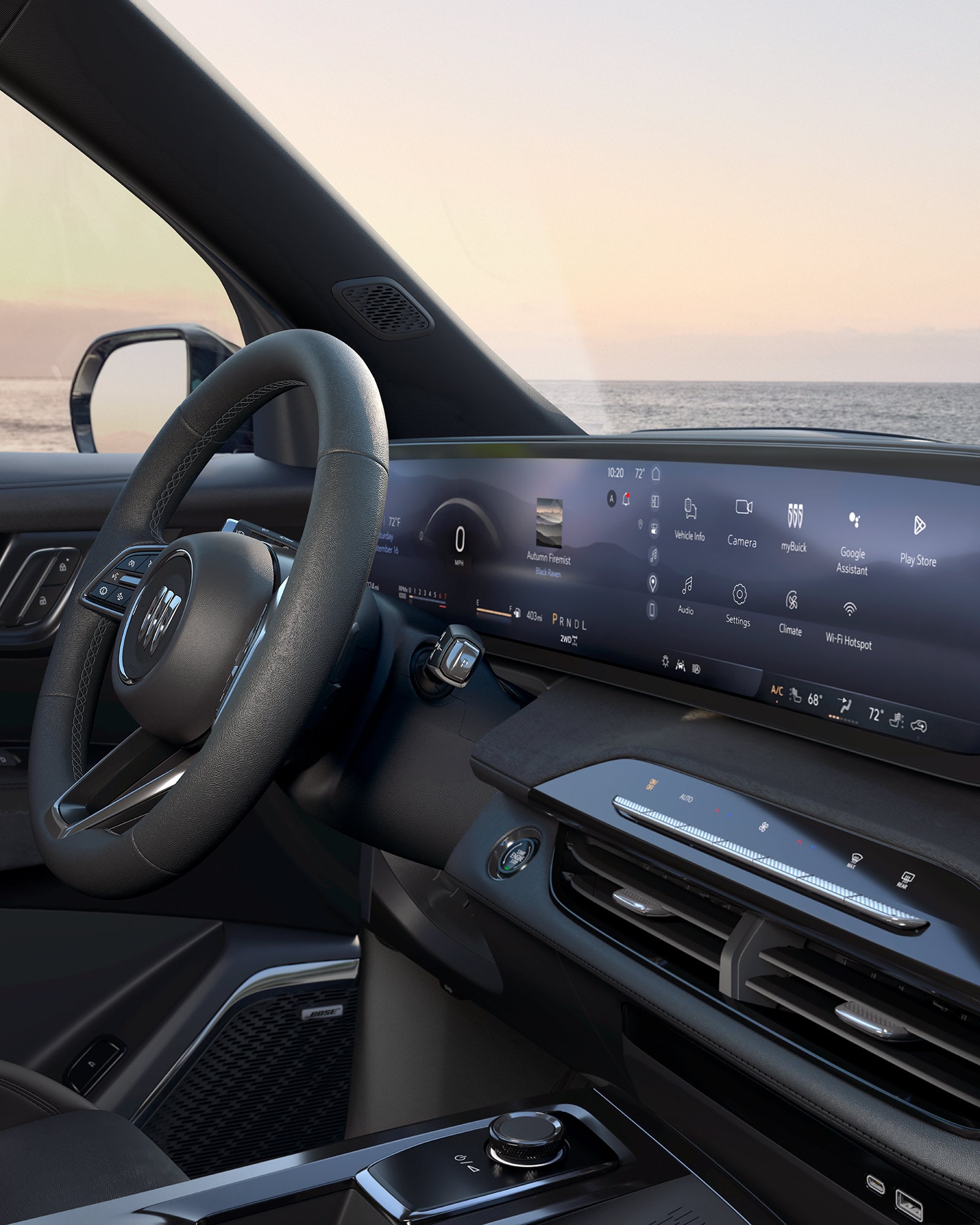 The Interior of a Buick Vehicle with a Steering Wheel, a Wide Digital Infotainment Screen, and the Ocean Outside