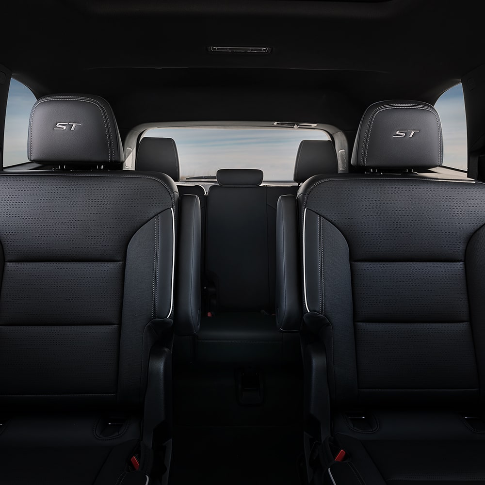 An Interior View of a Car's Second-Row Seating with Two Dark Gray Captain's Chairs and 'ST' Embroidery
